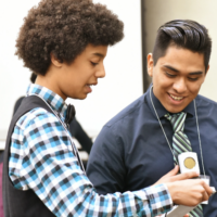 Image displays an high school student presenting their solutions from a project to a teacher at a Curtis Center conference.