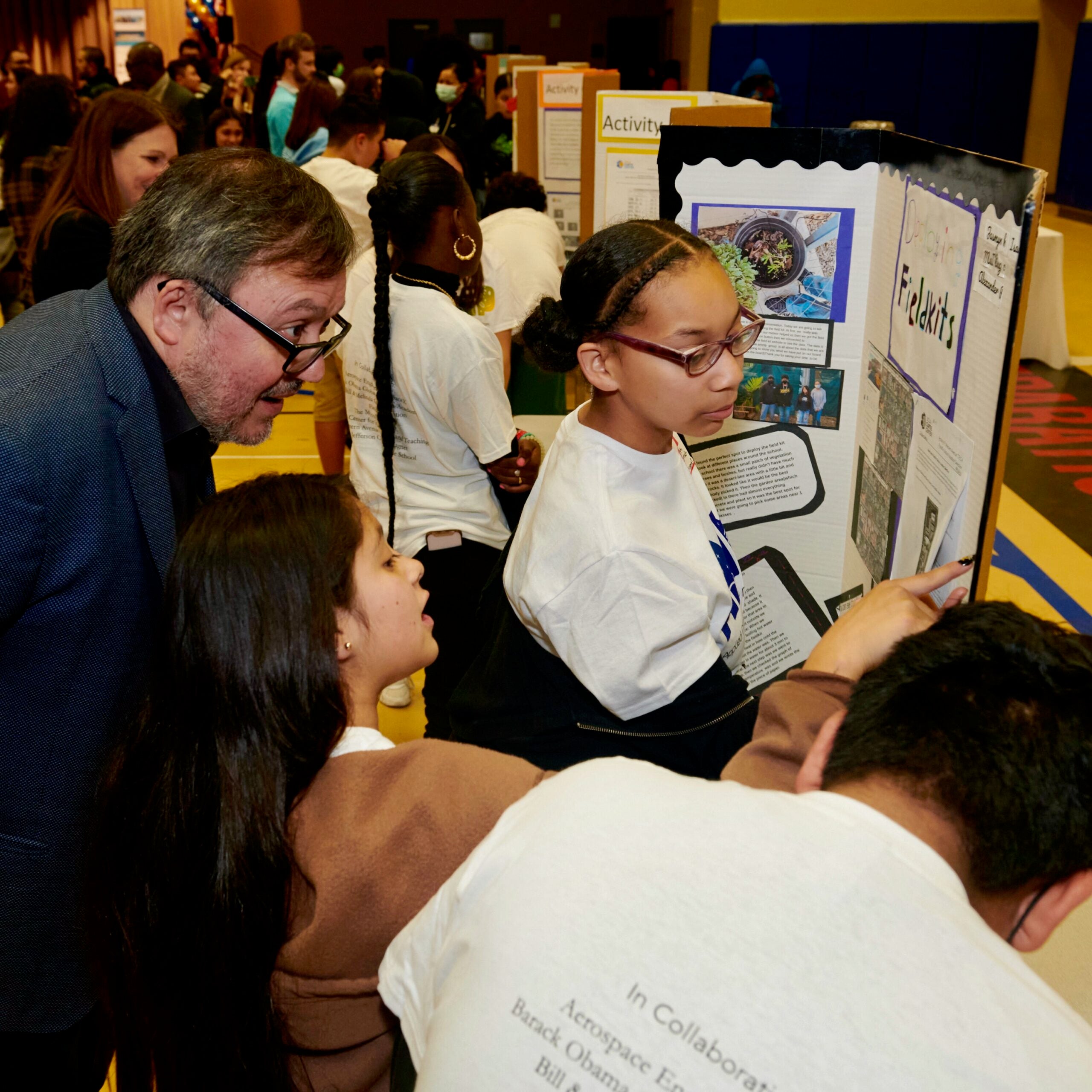 Image displays Miguel Garcia-Garibay, dean of Physical Science at UCLA, listening to students present the findings of their research investigations.